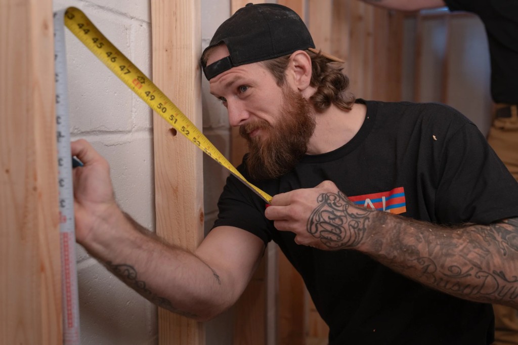 Neutral Electrician measuring a framed wall