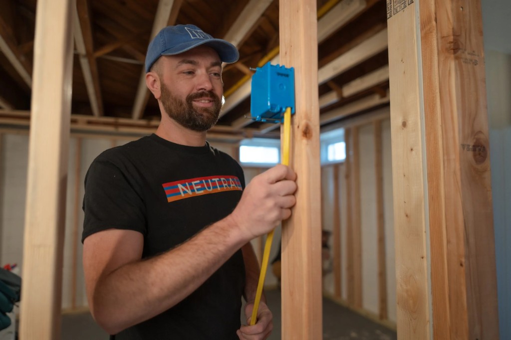 Neutral Electrician measuring wire in a wall frame